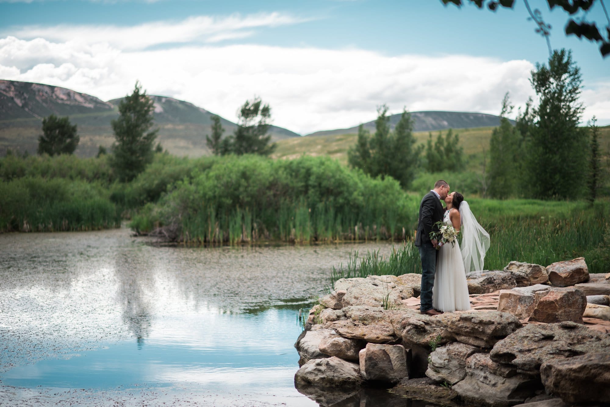 bride groom kissing at pond at Horse Creek Cattle Company